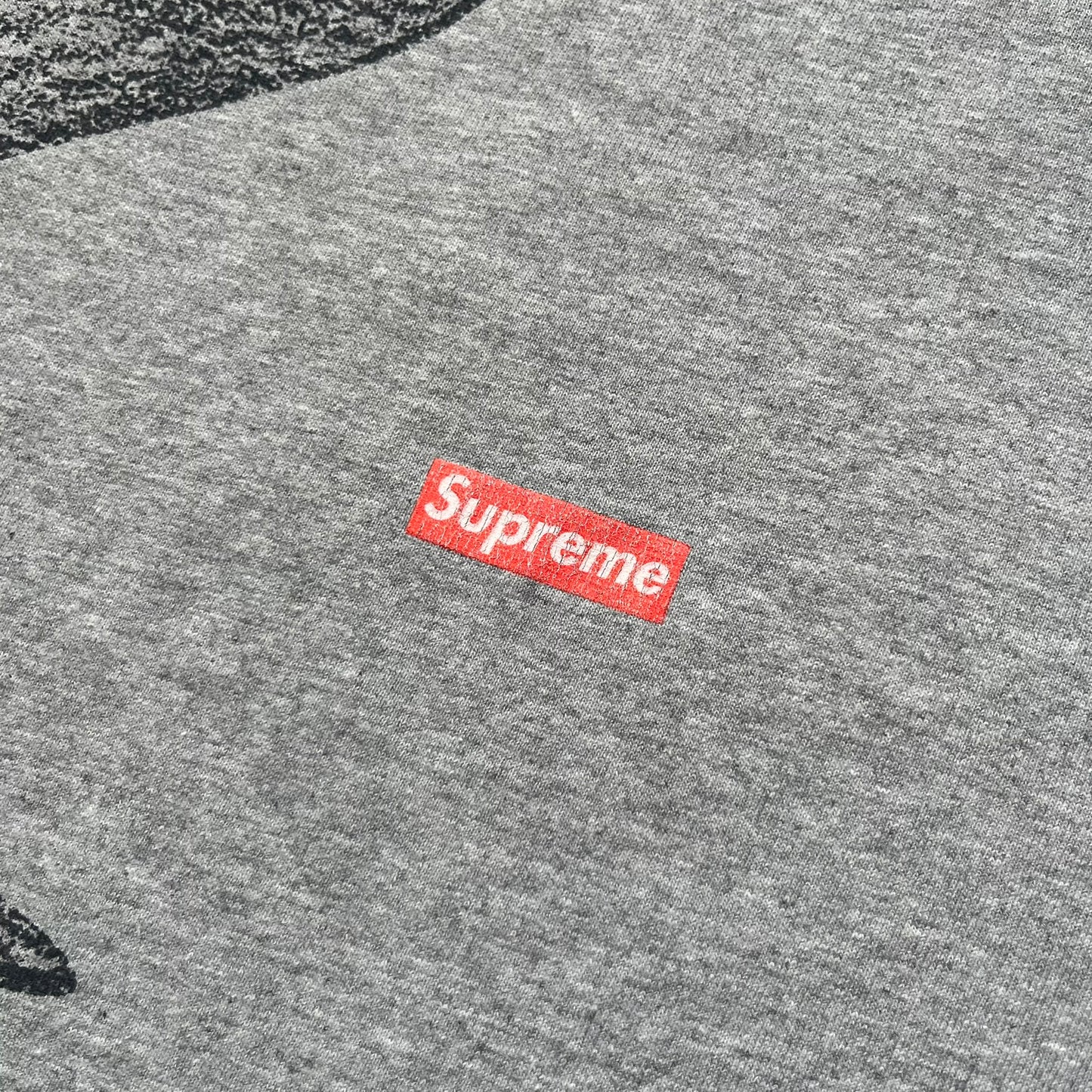 Supreme FW07 WTAPS “Live To Ride, Ride To Live” Gray Tee is a gray short-sleeve T-shirt released in Autumn/Winter 2007. The front features a black sketch of Robin on a skateboard with a small red Supreme logo beside it, while the upper back displays bold “Live To Ride, Ride To Live” text. The T-shirt was designed by Tetsu Nishiyama (WTAPS).