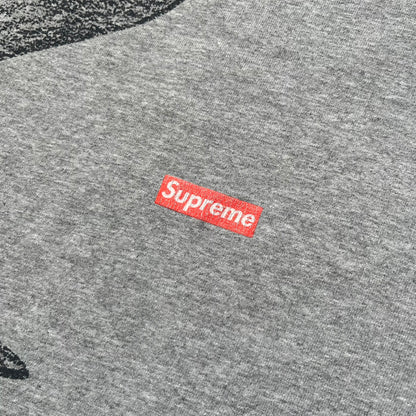 Supreme FW07 WTAPS “Live To Ride, Ride To Live” Gray Tee is a gray short-sleeve T-shirt released in Autumn/Winter 2007. The front features a black sketch of Robin on a skateboard with a small red Supreme logo beside it, while the upper back displays bold “Live To Ride, Ride To Live” text. The T-shirt was designed by Tetsu Nishiyama (WTAPS).