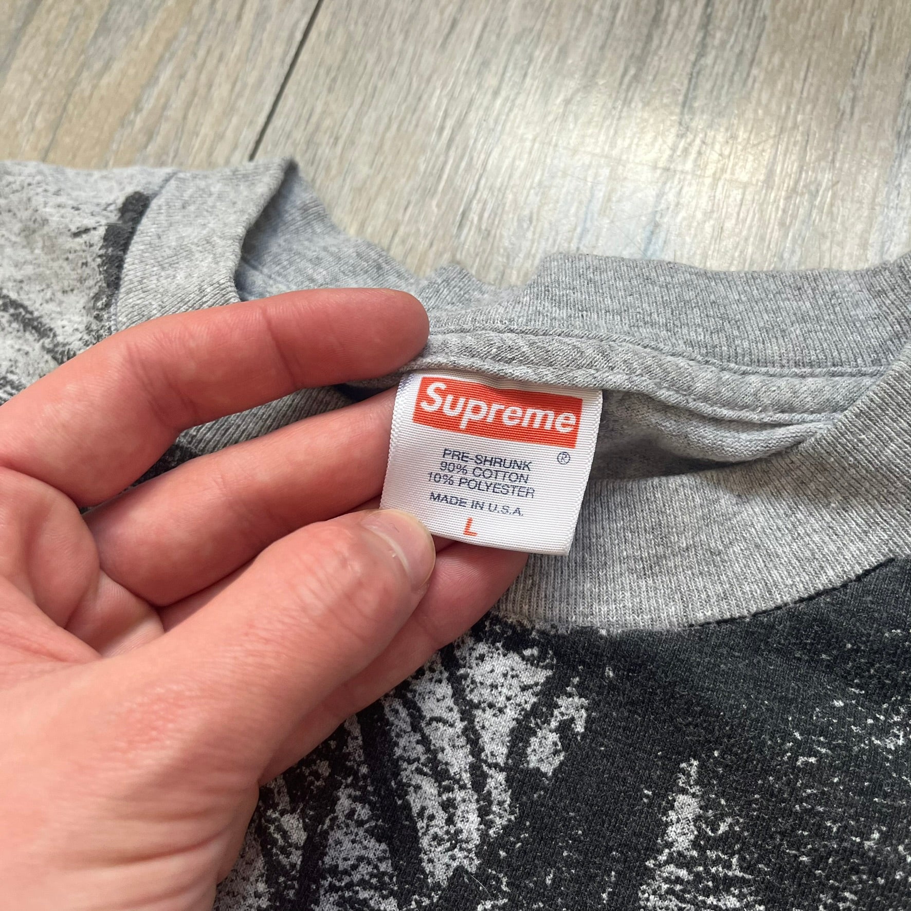 Supreme FW07 WTAPS “Live To Ride, Ride To Live” Gray Tee is a gray short-sleeve T-shirt released in Autumn/Winter 2007. The front features a black sketch of Robin on a skateboard with a small red Supreme logo beside it, while the upper back displays bold “Live To Ride, Ride To Live” text. The T-shirt was designed by Tetsu Nishiyama (WTAPS).