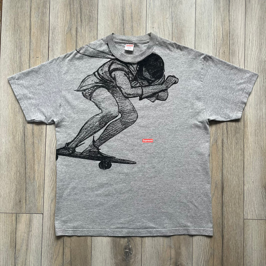 Supreme FW07 WTAPS “Live To Ride, Ride To Live” Gray Tee is a gray short-sleeve T-shirt released in Autumn/Winter 2007. The front features a black sketch of Robin on a skateboard with a small red Supreme logo beside it, while the upper back displays bold “Live To Ride, Ride To Live” text. The T-shirt was designed by Tetsu Nishiyama (WTAPS).