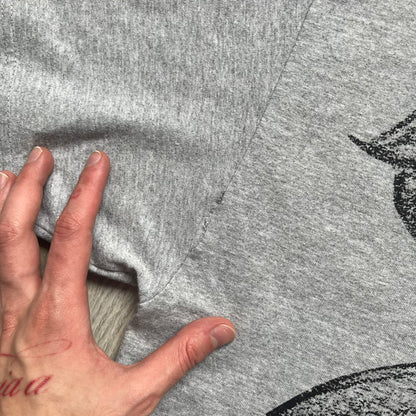 Supreme FW07 WTAPS “Live To Ride, Ride To Live” Gray Tee is a gray short-sleeve T-shirt released in Autumn/Winter 2007. The front features a black sketch of Robin on a skateboard with a small red Supreme logo beside it, while the upper back displays bold “Live To Ride, Ride To Live” text. The T-shirt was designed by Tetsu Nishiyama (WTAPS).