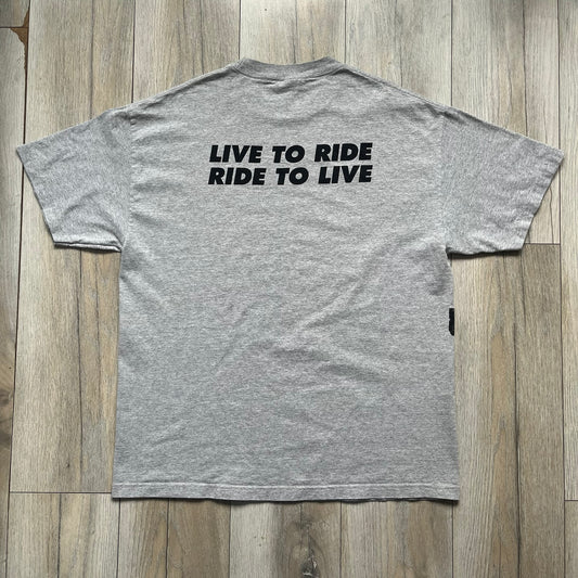 Supreme FW07 WTAPS “Live To Ride, Ride To Live” Gray Tee is a gray short-sleeve T-shirt released in Autumn/Winter 2007. The front features a black sketch of Robin on a skateboard with a small red Supreme logo beside it, while the upper back displays bold “Live To Ride, Ride To Live” text. The T-shirt was designed by Tetsu Nishiyama (WTAPS).
