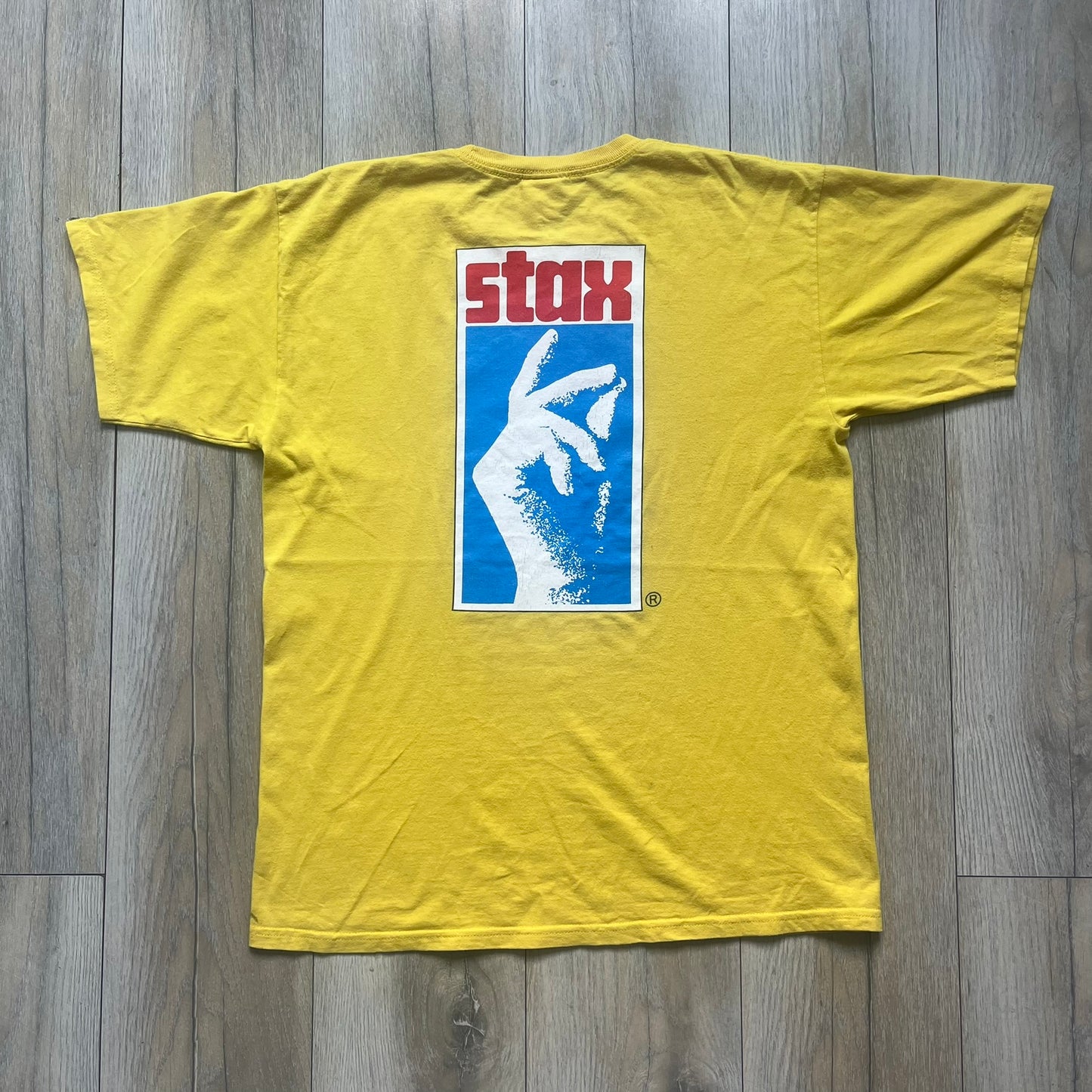 Supreme FW12 Stax Records Tee is a yellow T-shirt from the Fall/Winter 2012 collection. The front features small black Supreme text on the left chest. The back has a large Stax Records logo print with the blue and white hand graphic and red Stax text underneath. Concord Music Group licensing on the necktag.