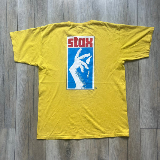 Supreme FW12 Stax Records Tee is a yellow T-shirt from the Fall/Winter 2012 collection. The front features small black Supreme text on the left chest. The back has a large Stax Records logo print with the blue and white hand graphic and red Stax text underneath. Concord Music Group licensing on the necktag.