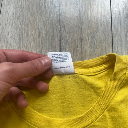 Supreme FW12 Stax Records Tee is a yellow T-shirt from the Fall/Winter 2012 collection. The front features small black Supreme text on the left chest. The back has a large Stax Records logo print with the blue and white hand graphic and red Stax text underneath. Concord Music Group licensing on the necktag.