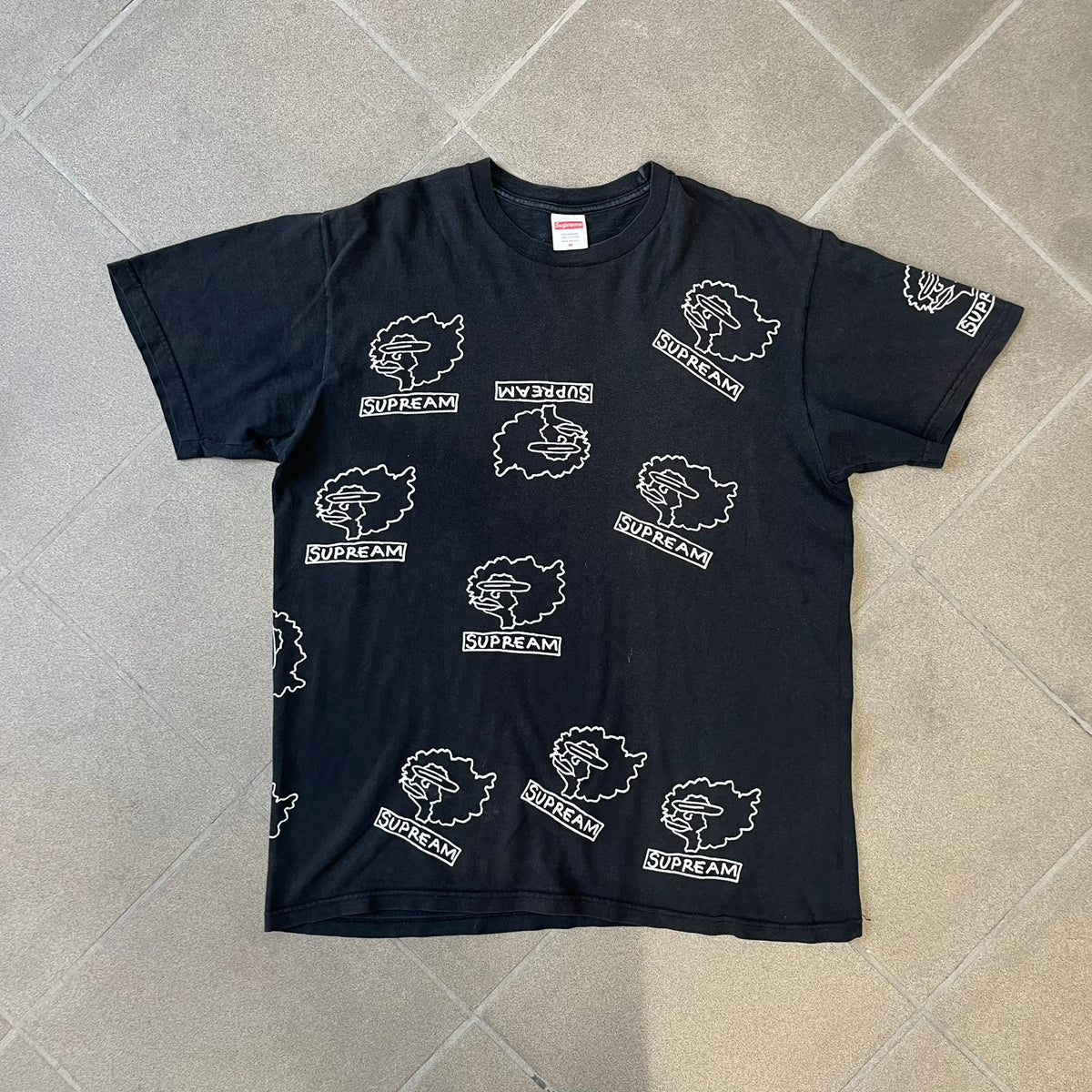Supreme FW17 Gonz Heads Tee is a black T-shirt from the Fall/Winter 2017 collection created in collaboration with Mark Gonzales (The Gonz). The tee features repeated white Gonz head graphics printed across both the front and back in different orientations. The shirt is made in the USA.