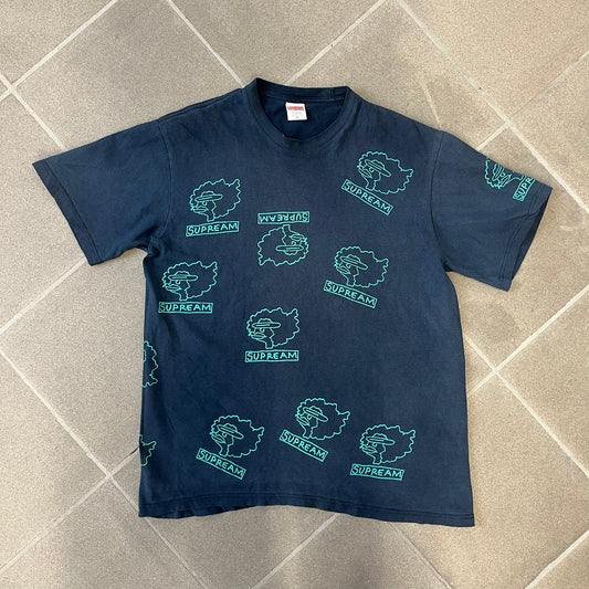 Supreme FW17 Gonz Heads Tee is a navy T-shirt from the Fall/Winter 2017 collection created in collaboration with Mark Gonzales (The Gonz). The tee features repeated green Gonz head graphics printed across both the front and back in different orientations. The shirt is made in the USA.
