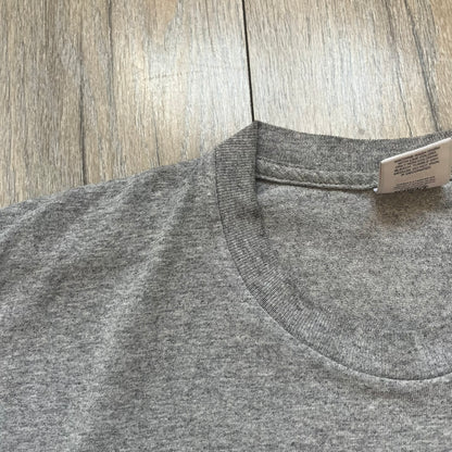 Supreme FW17 Scarface Blimp Gray Tee is a grey T-shirt from the Fall/Winter 2017 collection featuring a large front print from the film Scarface. The graphic shows the blimp scene with “The World Is Yours” text in black on a blue background, with a small red Supreme box logo printed below. Released in October 2017 as part of the Supreme x Scarface collaboration.