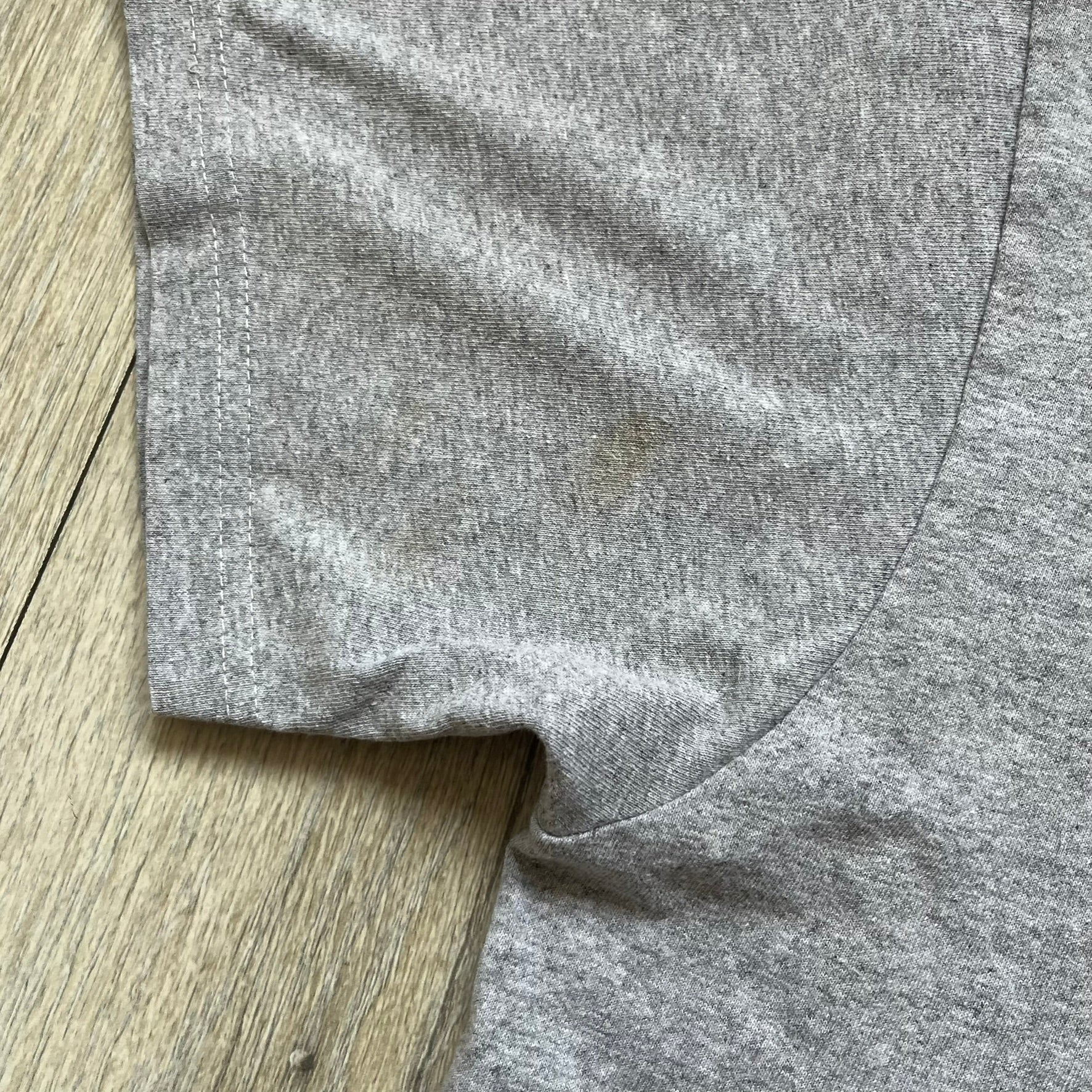 The Supreme Scarface Split Tee Heather Grey from Fall/Winter 2017 is constructed from cotton with a classic crewneck and short sleeves. The front displays Tony Montana in black and white with red Supreme branding across the image, while the back features text from the original 1983 film poster and a Supreme logo underneath. The neck tag carries official Scarface branding