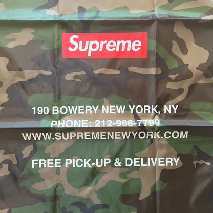 Supreme FW25 Woodland Camo laundry bag in Realtree AP camouflage, released as a limited gift during the first drop of the Fall/Winter 2025 season. Features 190 Bowery New York contact details, “Free Pick-up &amp; Delivery” text, and the iconic Supreme Box Logo on the top.