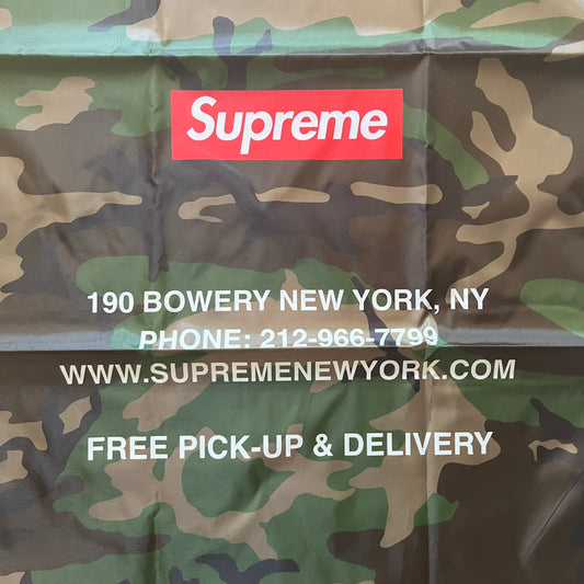 Supreme FW25 Woodland Camo laundry bag in Realtree AP camouflage, released as a limited gift during the first drop of the Fall/Winter 2025 season. Features 190 Bowery New York contact details, “Free Pick-up &amp; Delivery” text, and the iconic Supreme Box Logo on the top.