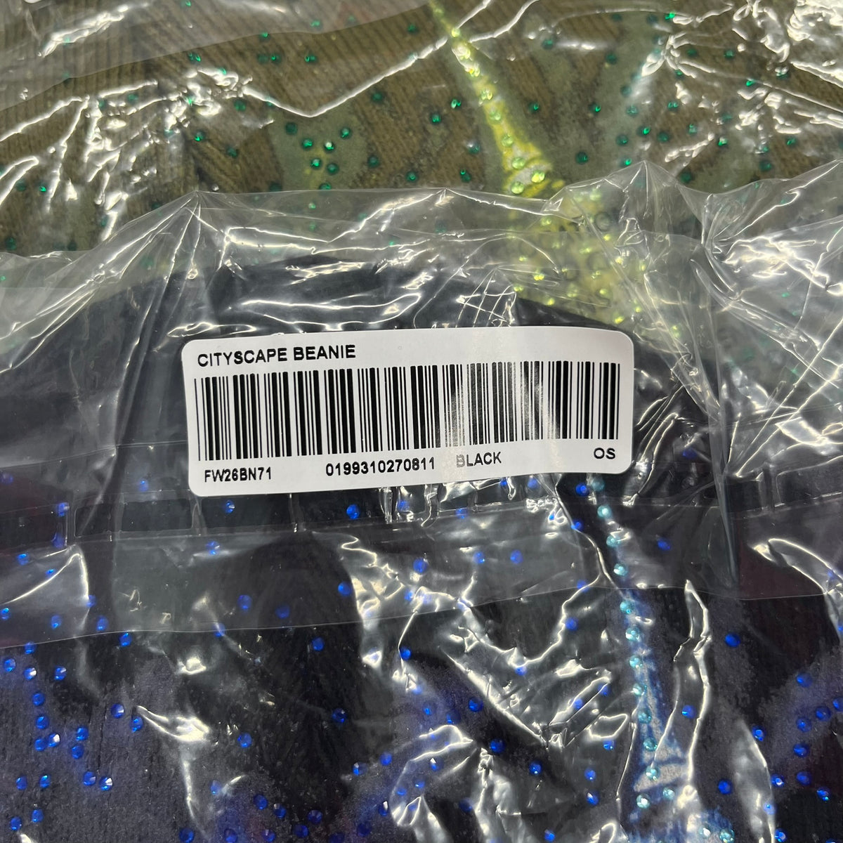 Supreme FW26 Cityscape Art Dealer Black Beanie is a black acrylic beanie with original artwork by Art Dealer, featuring a blue and white night city graphic with a moon and small stars across the sky on both sides. An old English-style Supreme logo sits on the front, and rhinestone appliqués in different sizes decorate the front and back. The print is stretchy, so any cracking effect that appears is just the print stretching with wear.