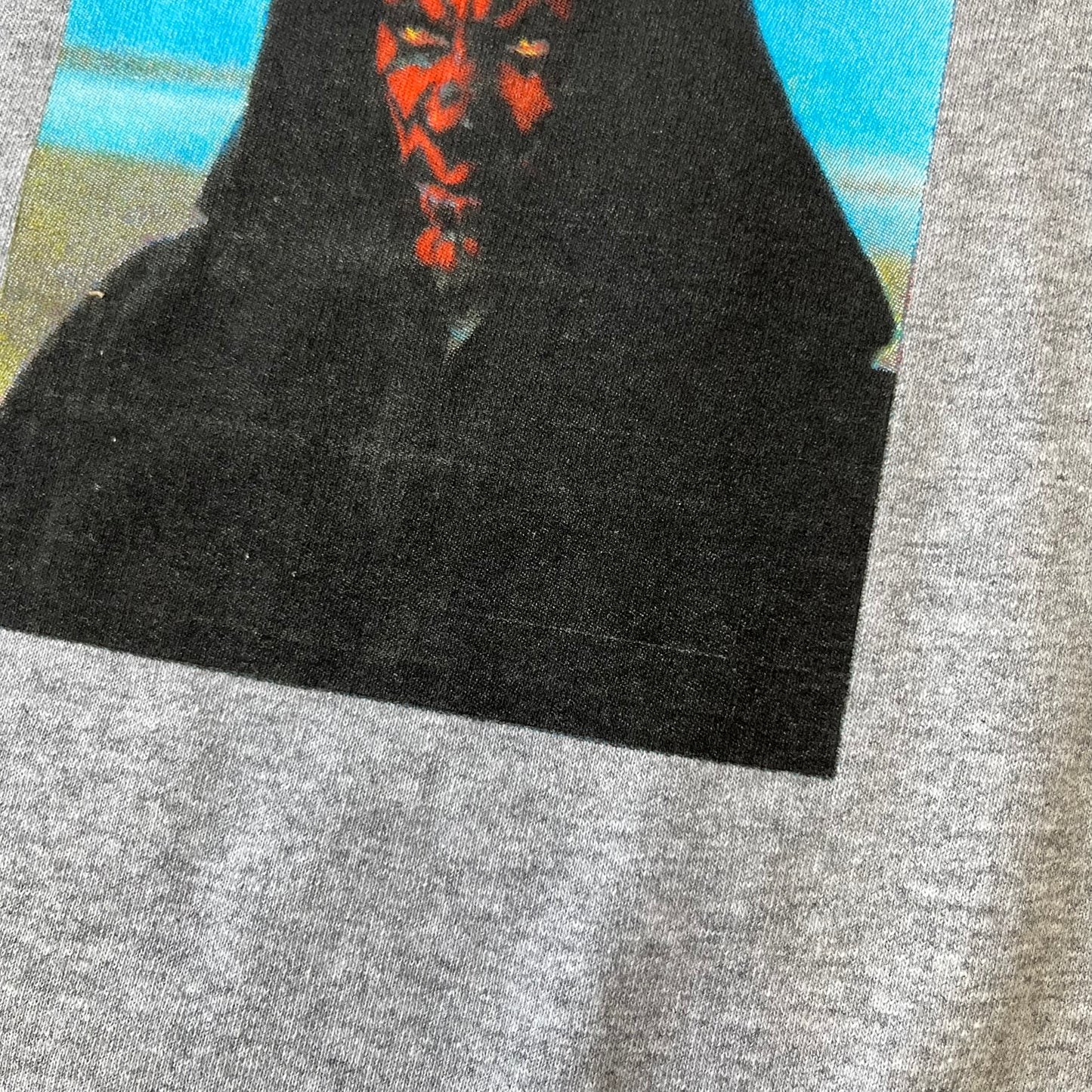 Supreme FW26 Darth Maul Sith Gray Tee features a black 90% cotton and 10% polyester T-shirt with a photo graphic of Darth Maul on a blue background. A white Supreme logo is printed above the graphic. Features a licensed Star Wars neck tag and is made in Honduras.