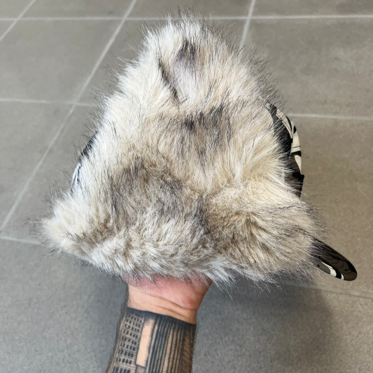Supreme FW26 GORE-TEX Earflap Predator Camo Camp Cap is a waterproof, breathable camp cap made from GORE-TEX 2-layer poly ripstop in a white, black, and brown camo pattern. It features a black Supreme box logo on the front, an embroidered graphic on the side, and a strap closure. The cap is lined with polar fleece, and the earflaps are lined with faux fur.