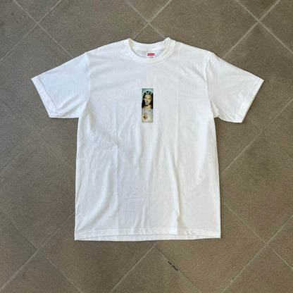Supreme FW26 Prayer Card Jesus Box Logo White Tee features a white 100% cotton T-shirt with a vertical Supreme box logo graphic on the front. The Supreme text is printed lightly over a graphic depicting the Sacred Heart of Jesus. Made in Honduras.
