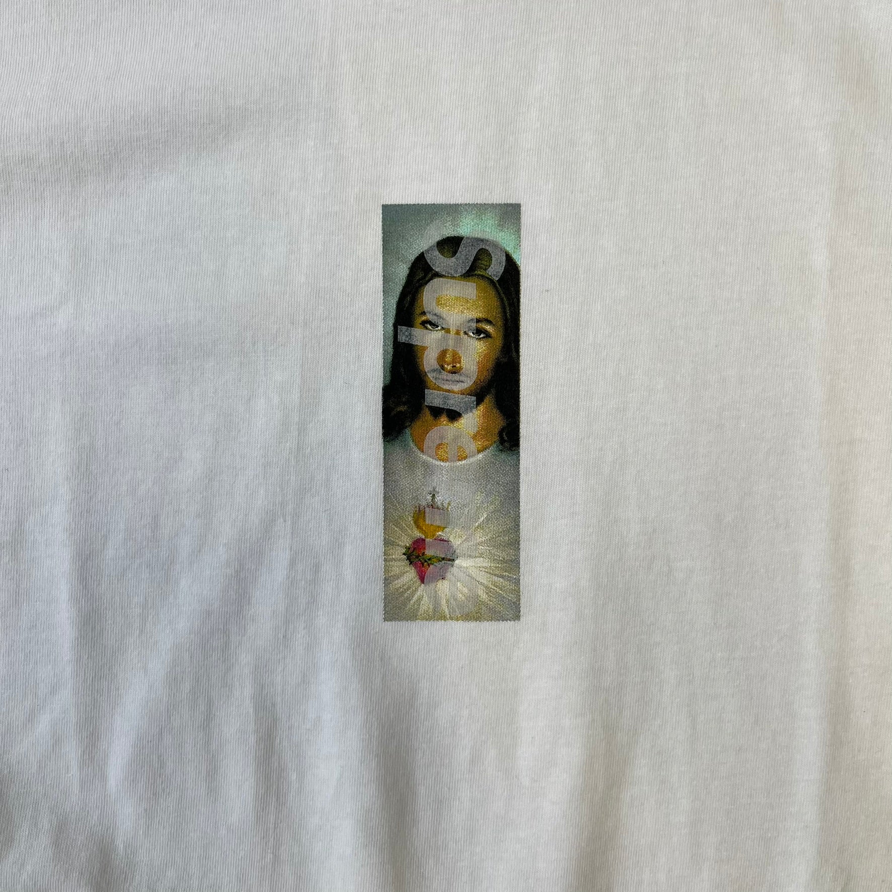 Supreme FW26 Prayer Card Jesus Box Logo White Tee features a white 100% cotton T-shirt with a vertical Supreme box logo graphic on the front. The Supreme text is printed lightly over a graphic depicting the Sacred Heart of Jesus. Made in Honduras.
