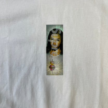 Supreme FW26 Prayer Card Jesus Box Logo White Tee features a white 100% cotton T-shirt with a vertical Supreme box logo graphic on the front. The Supreme text is printed lightly over a graphic depicting the Sacred Heart of Jesus. Made in Honduras.
