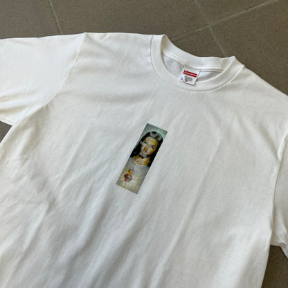 Supreme FW26 Prayer Card Jesus Box Logo White Tee features a white 100% cotton T-shirt with a vertical Supreme box logo graphic on the front. The Supreme text is printed lightly over a graphic depicting the Sacred Heart of Jesus. Made in Honduras.

