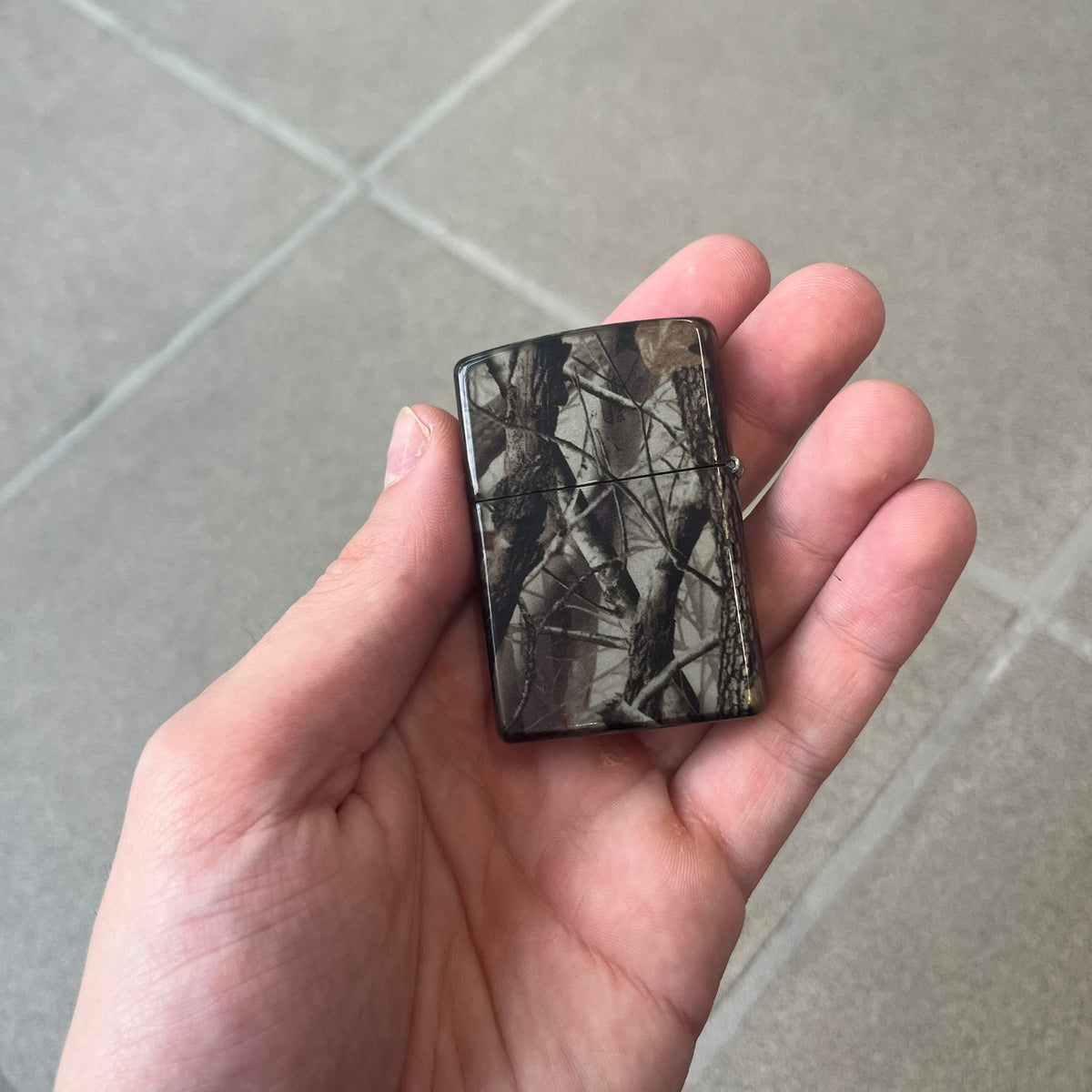 Supreme FW26 RealTree Camo Logo Zippo Lighter is an original Zippo featuring a full RealTree camo graphic with the Supreme box logo on the front. It comes with the original Zippo box and has never been filled.