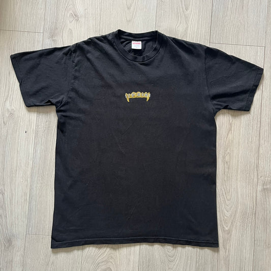 Supreme Fronts SS19 Black Tee released on February 21, 2019, as part of the brand’s Spring/Summer 2019 collection. Crafted from 100% cotton, it features a gold grill design with diamond fangs and a jeweled Supreme logo across the teeth. A standout graphic tee from Supreme’s early SS19 lineup.