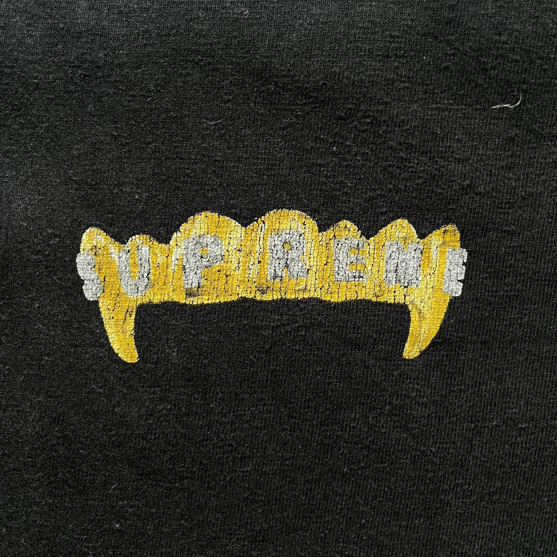 Supreme Fronts SS19 Black Tee released on February 21, 2019, as part of the brand’s Spring/Summer 2019 collection. Crafted from 100% cotton, it features a gold grill design with diamond fangs and a jeweled Supreme logo across the teeth. A standout graphic tee from Supreme’s early SS19 lineup.