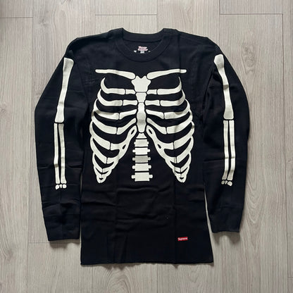 Supreme Hanes Bones Thermal Crew from FW25, crafted from 100% cotton in black with white bone graphics. Features a ribcage-inspired skeleton print on the front, matching arm bone designs on the sleeves, and a small Supreme logo near the hem. Released on October 23, 2025.