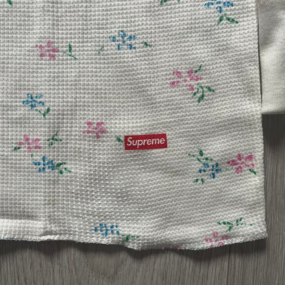 Supreme Hanes Bones Thermal Crew from FW25, crafted from 100% cotton in natural/white with black bone graphics and small floral all over print. Features a ribcage-inspired skeleton print on the front, matching arm bone designs on the sleeves, and a small Supreme logo near the hem. Released on October 23, 2025.