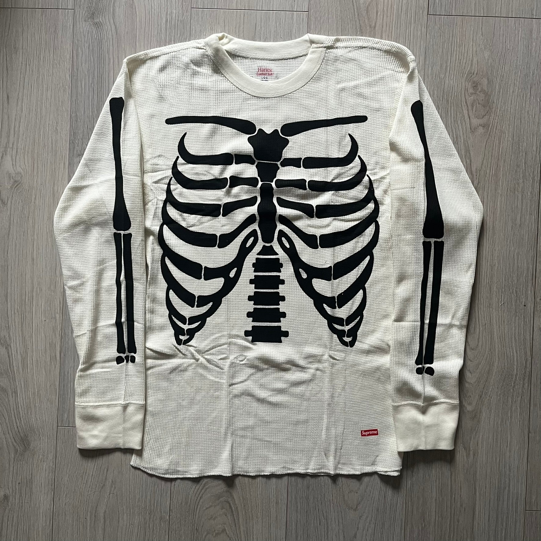 Supreme Hanes Bones Thermal Crew from FW25, crafted from 100% cotton in natural/white with black bone graphics. Features a ribcage-inspired skeleton print on the front, matching arm bone designs on the sleeves, and a small Supreme logo near the hem. Released on October 23, 2025.