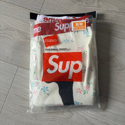 Supreme Hanes Bones Thermal Pant FW25 in natural/white with small floral all over print, crafted from 100% cotton. Features black skeletal bone prints running down both legs and a red elastic waistband with white Supreme branding throughout. Released October 23, 2025.