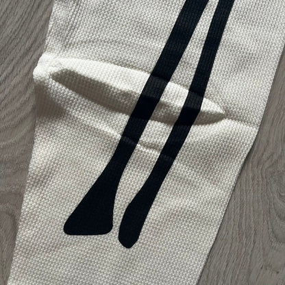 Supreme Hanes Bones Thermal Pant FW25 in natural/white, crafted from 100% cotton. Features black skeletal bone prints running down both legs and a red elastic waistband with white Supreme branding throughout. Released October 23, 2025.