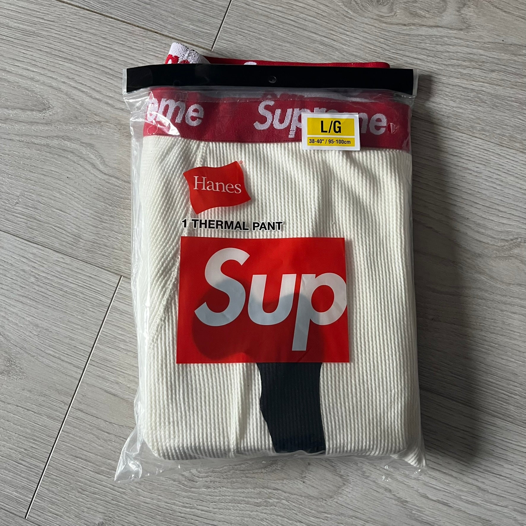 Supreme Hanes Bones Thermal Pant FW25 in natural/white, crafted from 100% cotton. Features black skeletal bone prints running down both legs and a red elastic waistband with white Supreme branding throughout. Released October 23, 2025.