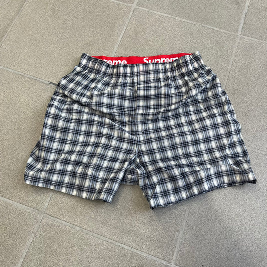 Supreme Hanes FW26 Plaid Boxers feature a plaid pattern and a red Supreme elastic waistband concealed inside. Made from 55% cotton and 45% polyester with Hanes Comfort Flex construction. Pink, grey, blue, and yellow colorways.