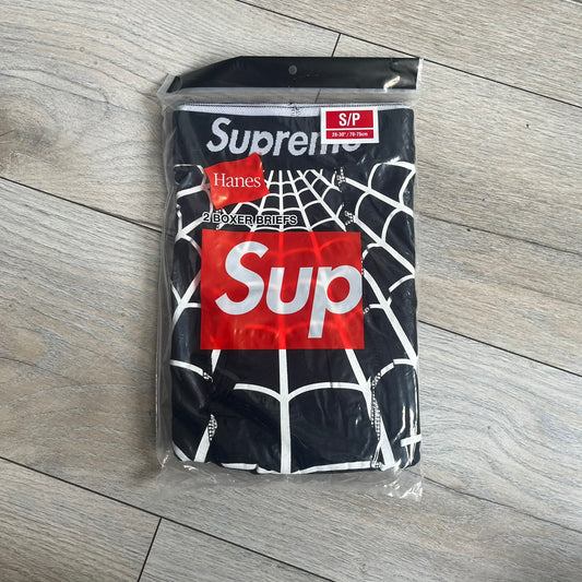 Supreme Hanes SS26 Spider-Man Black Boxer Briefs are made of cotton with a stretch fit. Features a black elastic waistband with white Supreme logo text and an all-over white web print. Classic Hanes base model a Spider-Man twist.
