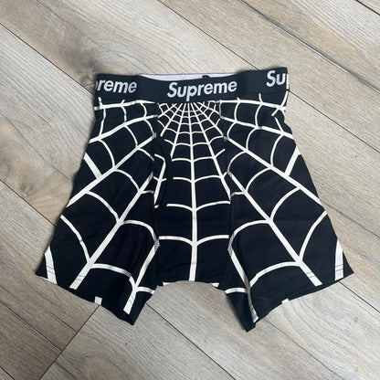 Supreme Hanes SS26 Spider-Man Black Boxer Briefs are made of cotton with a stretch fit. Features a black elastic waistband with white Supreme logo text and an all-over white web print. Classic Hanes base model a Spider-Man twist.
