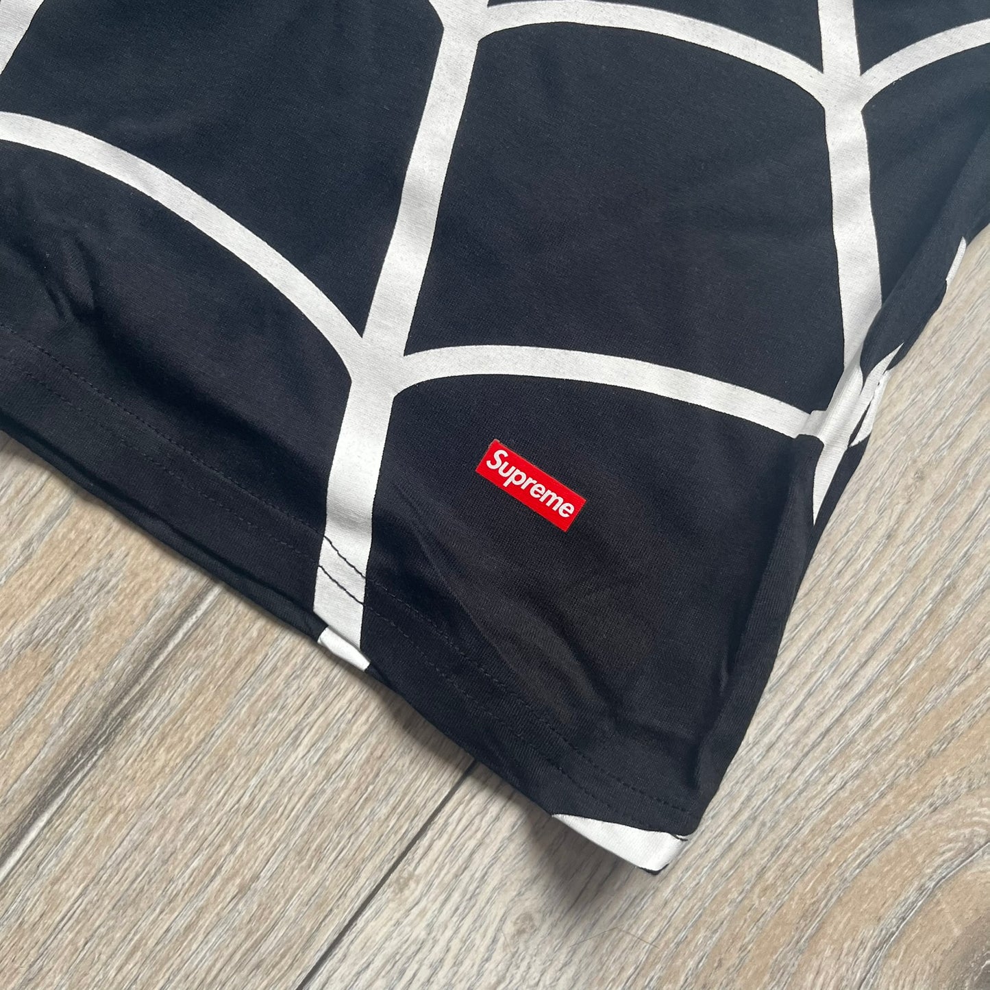 Supreme Hanes SS26 Spider-Man Black Tagless Tee is a black all-cotton crewneck T-shirt from the Spring/Summer 2026 collection, produced on a Hanes tagless blank. The shirt features an all-over white web print covering the front, back, and sleeves, with a small red Supreme stamp logo printed near the bottom corner.