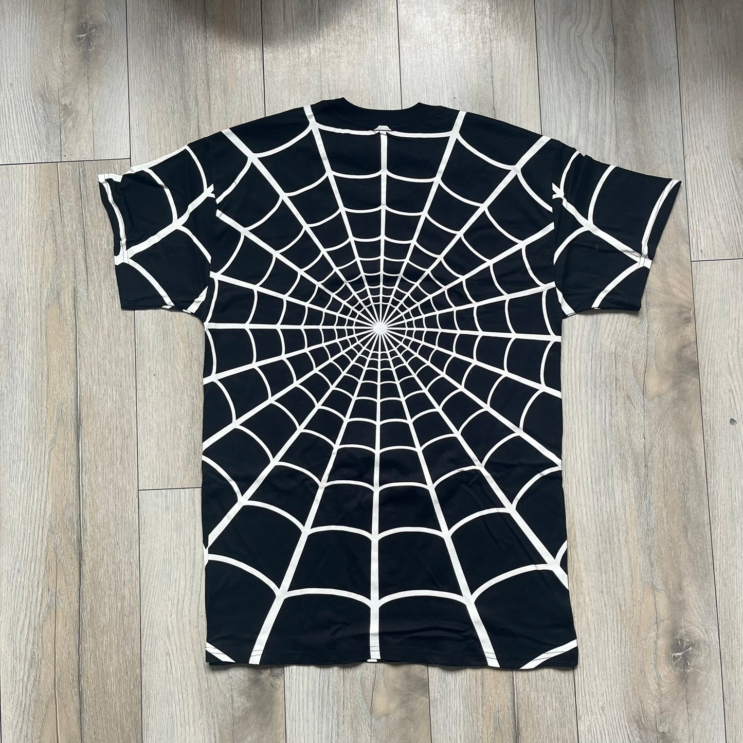 Supreme Hanes SS26 Spider-Man Black Tagless Tee is a black all-cotton crewneck T-shirt from the Spring/Summer 2026 collection, produced on a Hanes tagless blank. The shirt features an all-over white web print covering the front, back, and sleeves, with a small red Supreme stamp logo printed near the bottom corner.