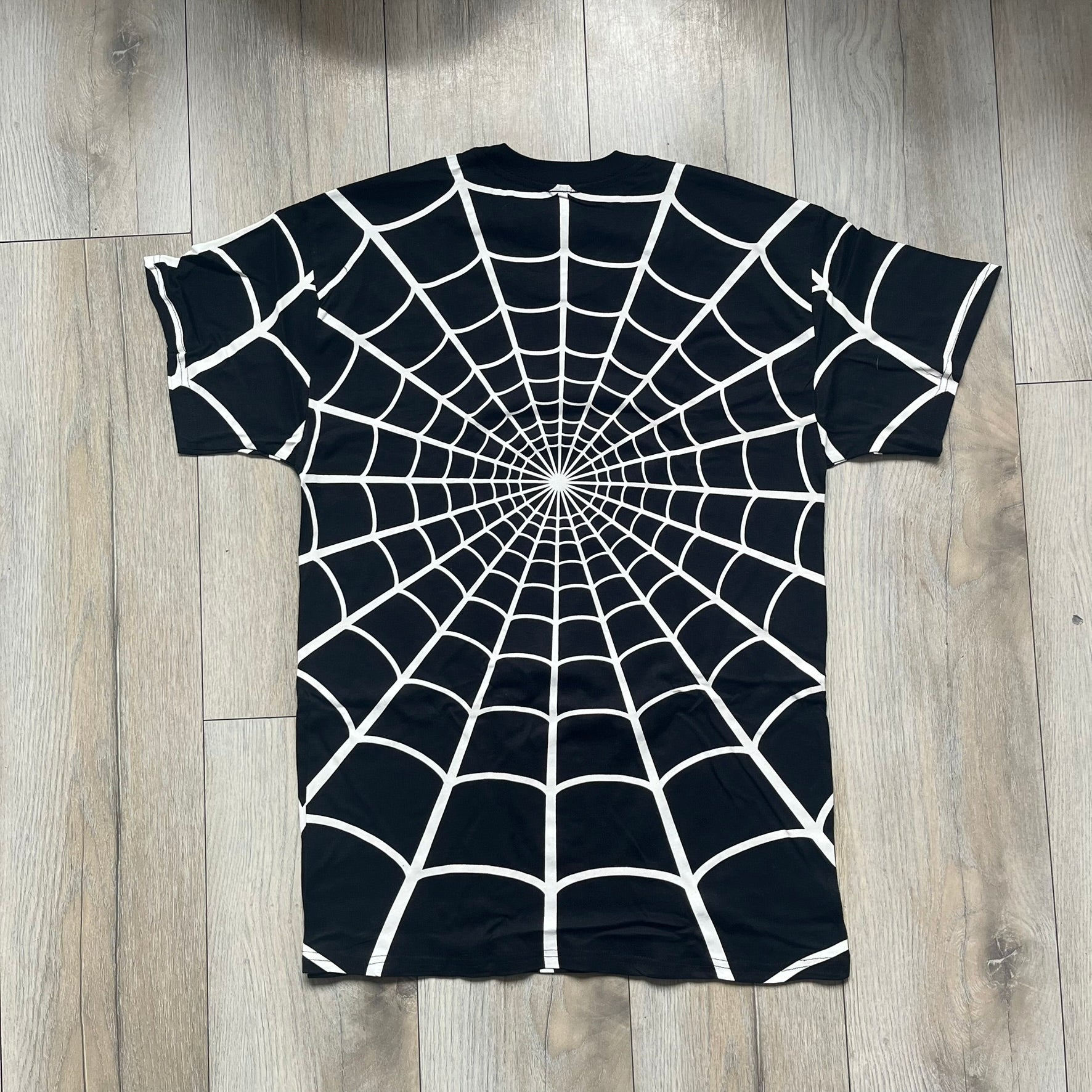 Supreme Hanes SS26 Spider-Man Black Tagless Tee is a black all-cotton crewneck T-shirt from the Spring/Summer 2026 collection, produced on a Hanes tagless blank. The shirt features an all-over white web print covering the front, back, and sleeves, with a small red Supreme stamp logo printed near the bottom corner.