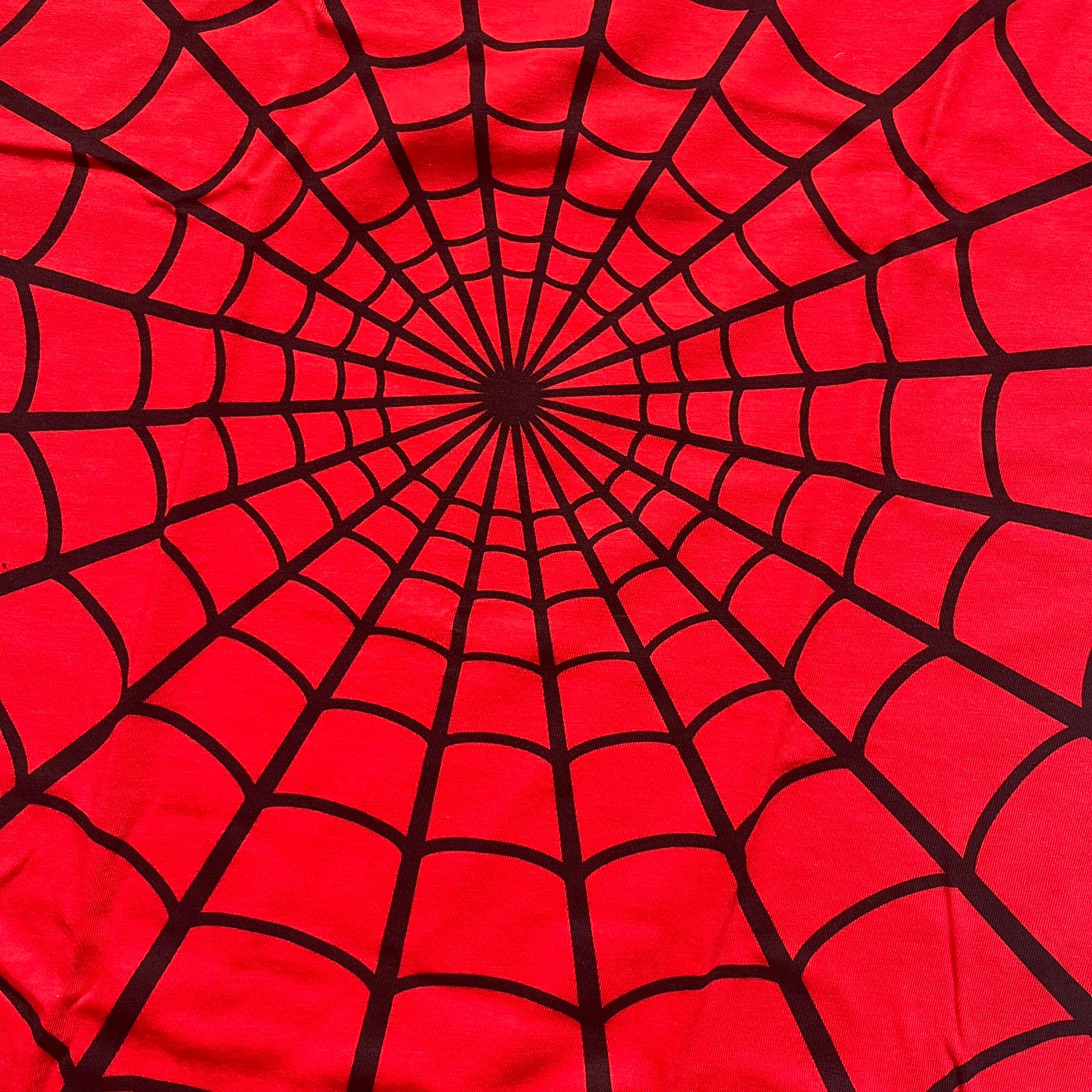 Supreme Hanes SS26 Spider-Man Red Tagless Tee is a red all-cotton crewneck T-shirt from the Spring/Summer 2026 collection, produced on a Hanes tagless blank. The shirt features an all-over black web print covering the front, back, and sleeves, with a small red Supreme stamp logo printed near the bottom corner.