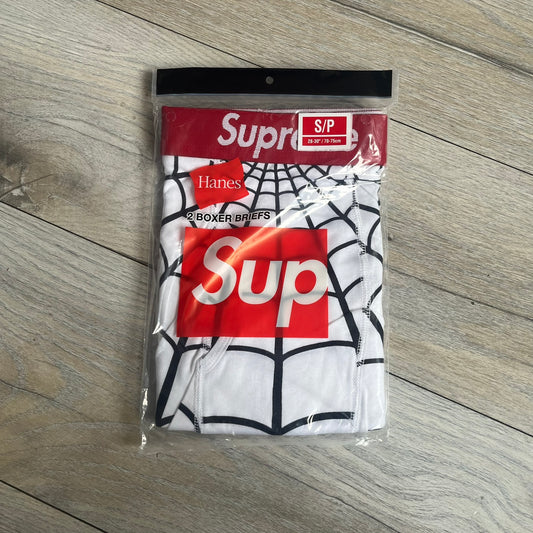 Supreme Hanes SS26 Spider-Man White Boxer Briefs are made of cotton with a stretch fit. Features a red elastic waistband with white Supreme logo text and an all-over black web print. Classic Hanes base model a Spider-Man twist.