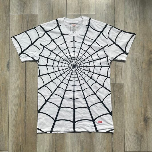 Supreme Hanes SS26 Spider-Man White Tagless Tee is a white all-cotton crewneck T-shirt from the Spring/Summer 2026 collection, produced on a Hanes tagless blank. The shirt features an all-over black web print covering the front, back, and sleeves, with a small red Supreme stamp logo printed near the bottom corner.