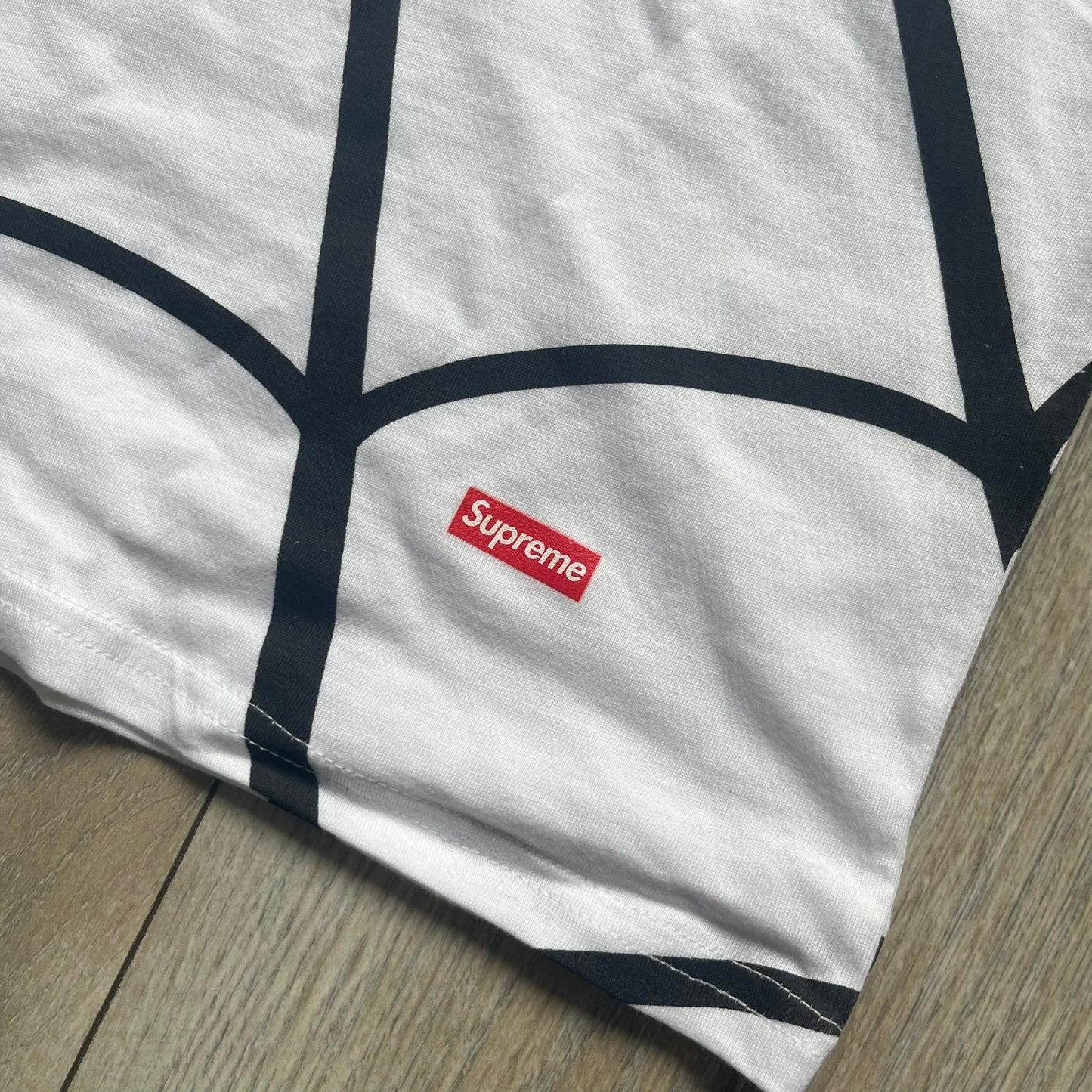 Supreme Hanes SS26 Spider-Man White Tagless Tee is a white all-cotton crewneck T-shirt from the Spring/Summer 2026 collection, produced on a Hanes tagless blank. The shirt features an all-over black web print covering the front, back, and sleeves, with a small red Supreme stamp logo printed near the bottom corner.