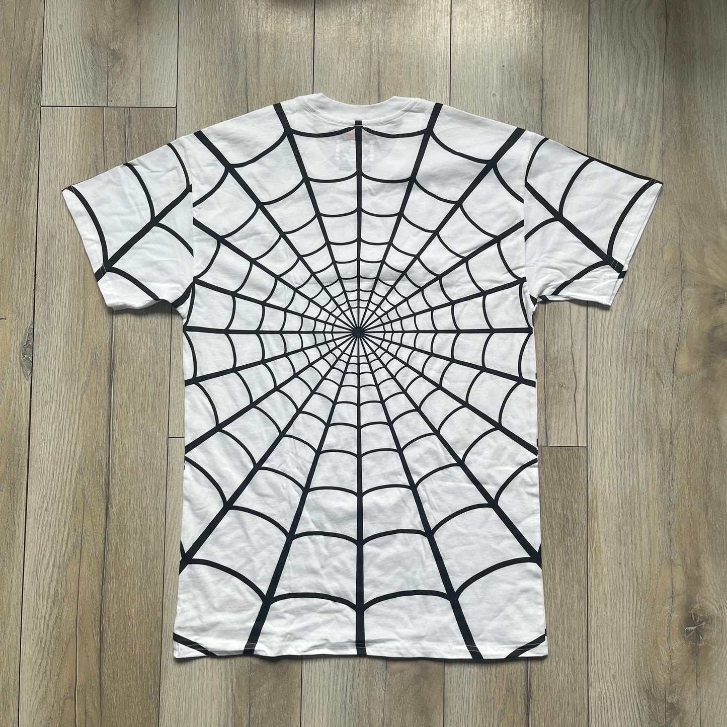 Supreme Hanes SS26 Spider-Man White Tagless Tee is a white all-cotton crewneck T-shirt from the Spring/Summer 2026 collection, produced on a Hanes tagless blank. The shirt features an all-over black web print covering the front, back, and sleeves, with a small red Supreme stamp logo printed near the bottom corner.
