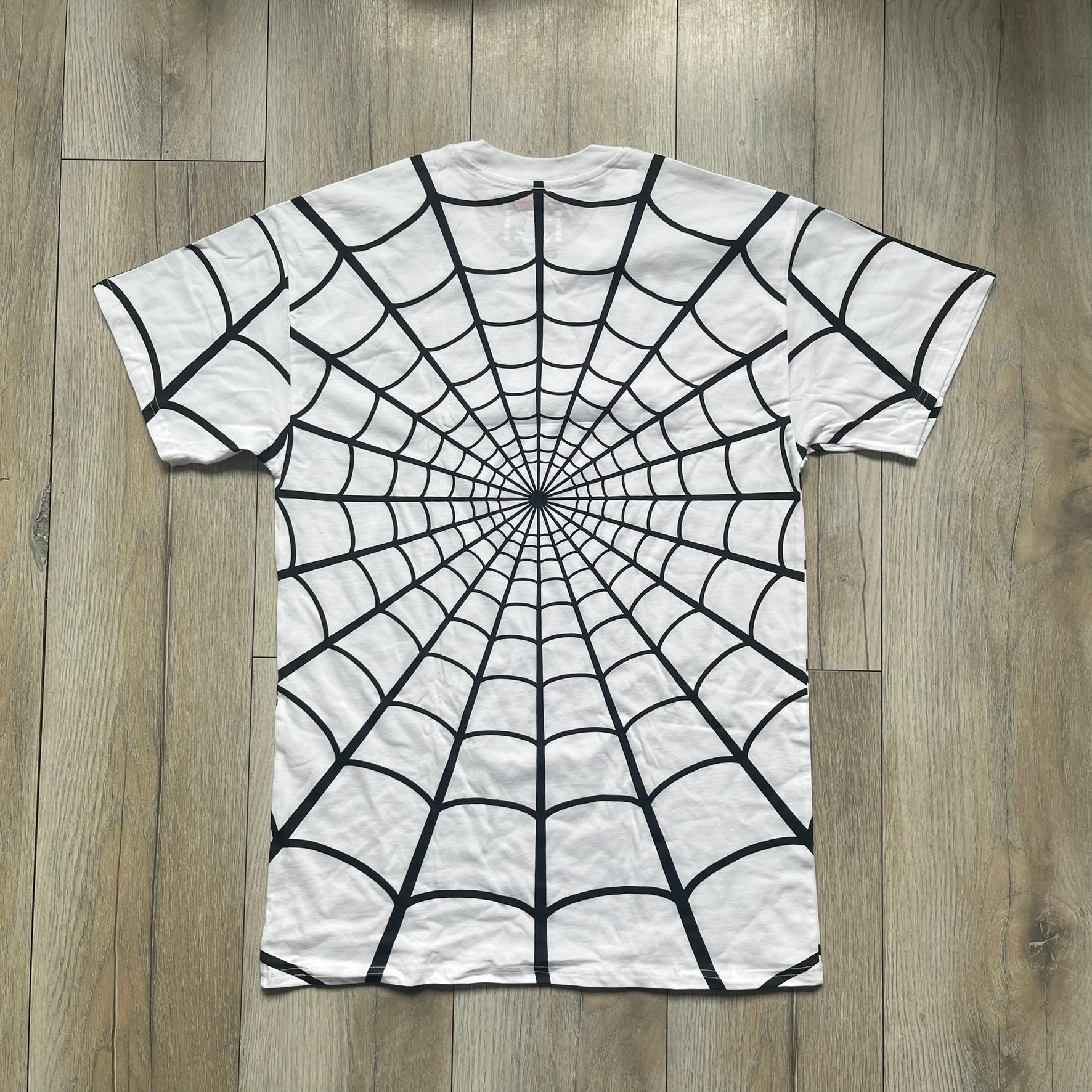 Supreme Hanes SS26 Spider-Man White Tagless Tee is a white all-cotton crewneck T-shirt from the Spring/Summer 2026 collection, produced on a Hanes tagless blank. The shirt features an all-over black web print covering the front, back, and sleeves, with a small red Supreme stamp logo printed near the bottom corner.