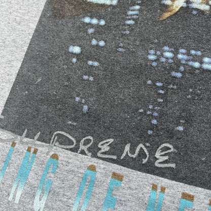 Supreme King of New York SS19 Gray Tee is a heather gray T-shirt released on February 21, 2019, as part of the SS19 collection. The front features an edited King of New York movie cover graphic with Christopher Walken’s name removed and replaced by handwritten-style “Supreme” and “C. Walken” text. The print is based on the original film cover artwork.