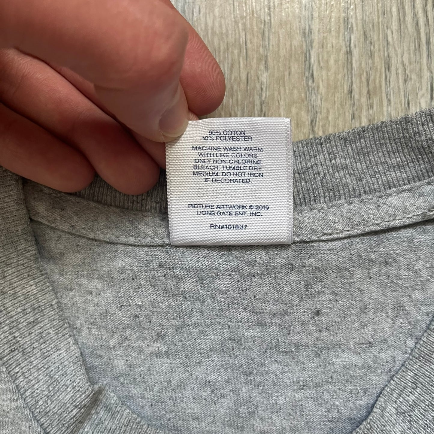 Supreme King of New York SS19 Gray Tee is a heather gray T-shirt released on February 21, 2019, as part of the SS19 collection. The front features an edited King of New York movie cover graphic with Christopher Walken’s name removed and replaced by handwritten-style “Supreme” and “C. Walken” text. The print is based on the original film cover artwork.