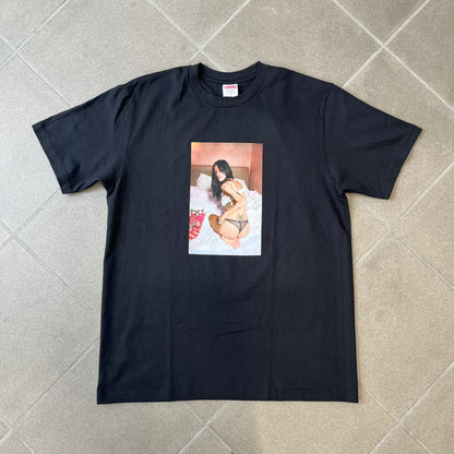 Product description:
Supreme Larry Clark FW26 Black Neighbor Tee is a black, 100% cotton T-shirt featuring a front photograph by Larry Clark of Gabbriette (Gabriella Leigh Bechtel) seated in underwear on a bed beside a red Supreme skateboard. The back displays hand-drawn-style white text reading "Love Thy Neighbor, Larry Clark 2026, Supreme."