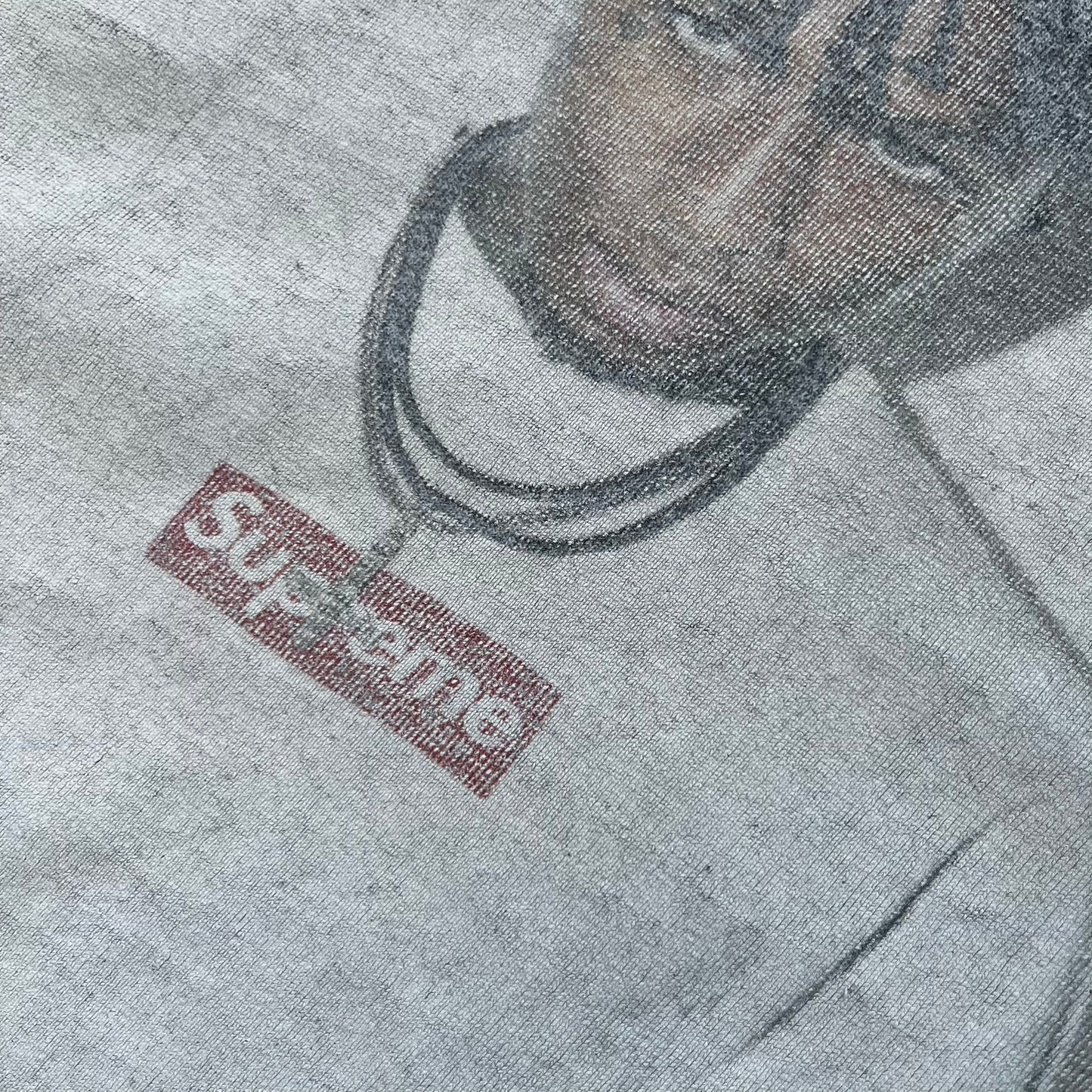 Supreme NBA Youngboy FW23 Gray Tee is a gray crew-neck T-shirt made in the USA from 100% cotton. The front features a multicolor graphic print of NBA Youngboy wearing the Supreme Box Logo tee. The shirt has short sleeves and a regular fit.