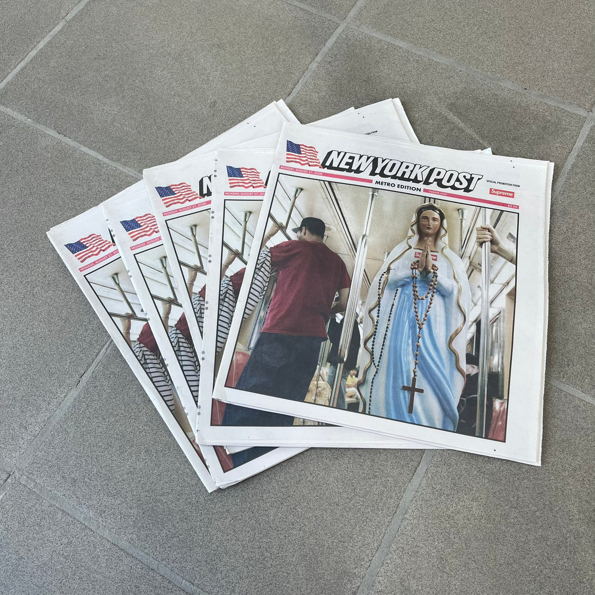 Supreme New York Post Newspaper “Late City Final Edition” from Fall/Winter 2026, released on August 17th, 2026. Features the features a religious statue with iconic Supreme box logo printed on it. On the back there's a "Deliver US From Evil". Includes the full original newspaper, with only the cover designed by Supreme.