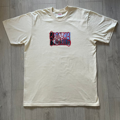 Natural Supreme tee from the FW23 season showcasing the “Payment” design. The front graphic depicts a pile of GBP banknotes with a large red graffiti-style Supreme tag layered across. A clean and minimalistic yet striking piece from the collection.
