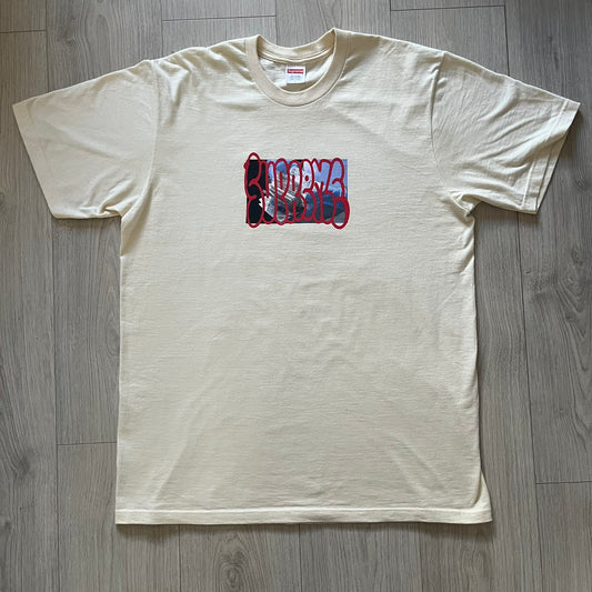 Natural Supreme tee from the FW23 season showcasing the “Payment” design. The front graphic depicts a pile of GBP banknotes with a large red graffiti-style Supreme tag layered across. A clean and minimalistic yet striking piece from the collection.